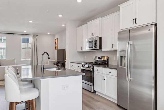 8678 London Cir NE Unit B, Blaine, MN 55449 - kitchen with light wood finished floors, a sink, white cabinetry, stainless steel appliances, and a kitchen island with sink