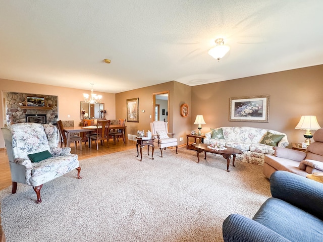 living room with carpet floors, baseboards, a notable chandelier, and a stone fireplace