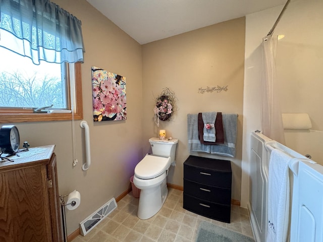 bathroom featuring toilet, baseboards, visible vents, and a shower with shower curtain