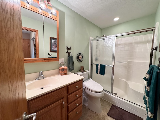 bathroom with vanity, toilet, a textured ceiling, tile patterned floors, and a stall shower