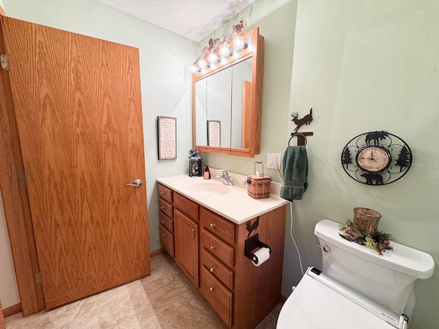 bathroom with toilet, a textured ceiling, and vanity