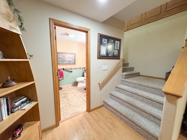 staircase with baseboards and wood finished floors