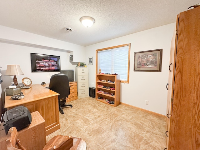 office space with baseboards, a textured ceiling, and visible vents