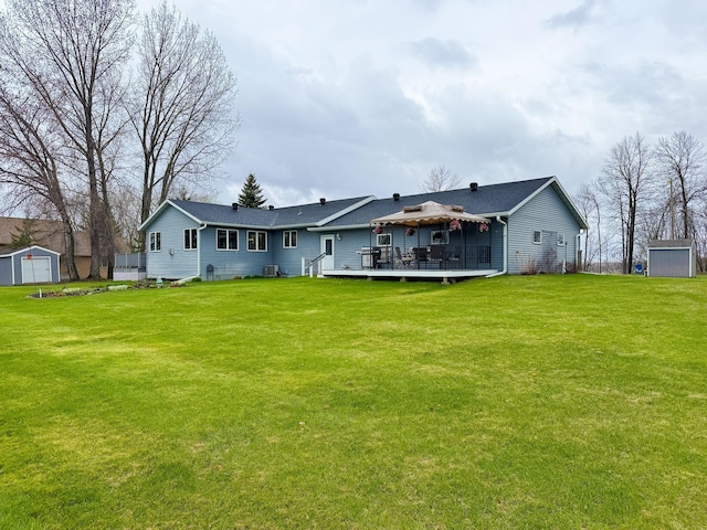 back of property with a gazebo, a lawn, an outbuilding, and a deck