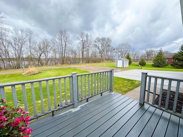 wooden deck featuring a storage unit, a lawn, and an outbuilding