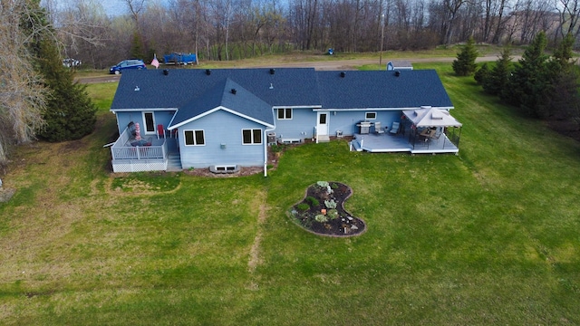 rear view of house featuring a lawn, a deck, and roof with shingles