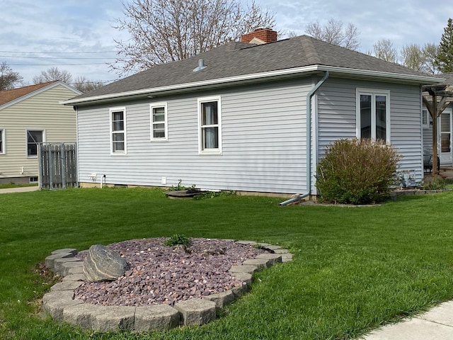 view of property exterior with a yard, a chimney, and a shingled roof