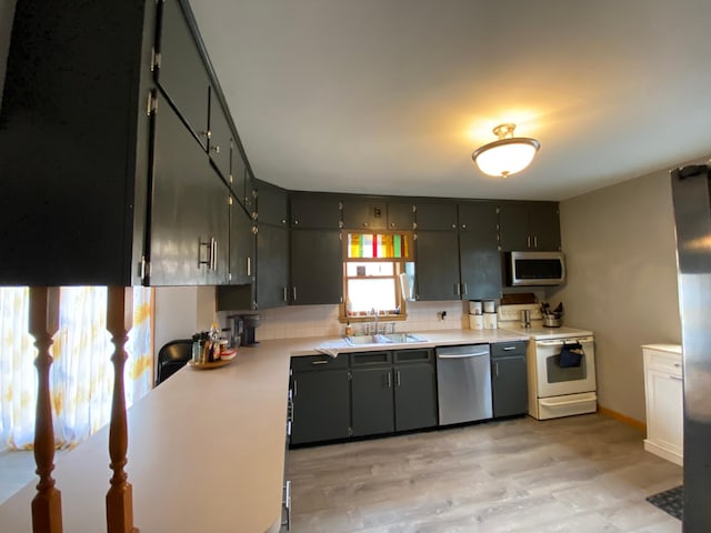 kitchen with decorative backsplash, light wood-style floors, light countertops, a sink, and stainless steel appliances