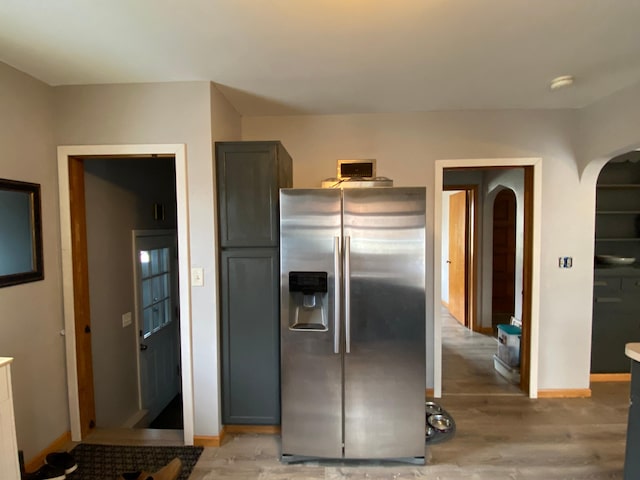 kitchen featuring light wood-style floors, arched walkways, baseboards, and stainless steel refrigerator with ice dispenser