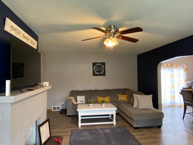 living area with ceiling fan, visible vents, and a fireplace