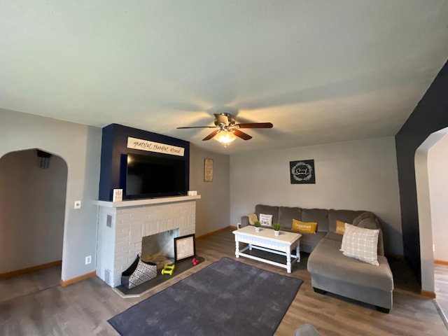 living area featuring arched walkways, ceiling fan, and wood finished floors
