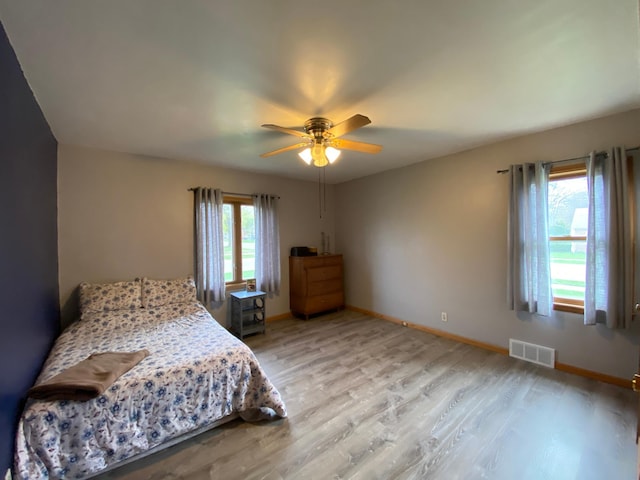 bedroom featuring visible vents, a ceiling fan, light wood-style flooring, and baseboards