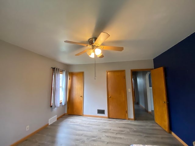 unfurnished bedroom with visible vents, light wood-style flooring, baseboards, and ceiling fan