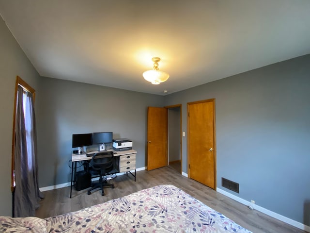 bedroom with baseboards, visible vents, and wood finished floors