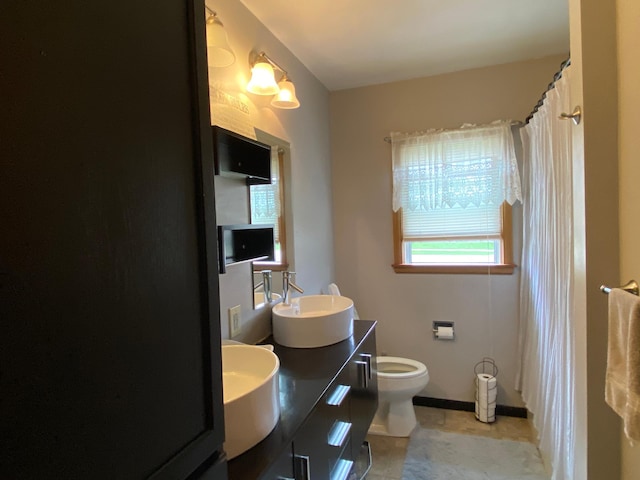bathroom with a sink, double vanity, toilet, tile patterned floors, and baseboards