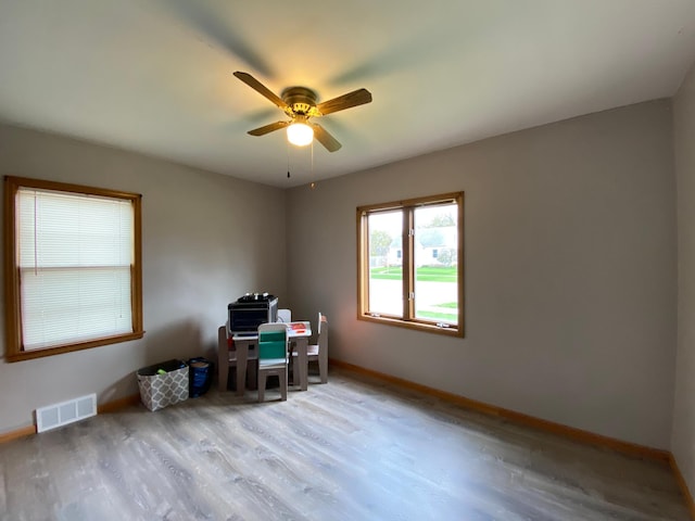 home office with baseboards, a ceiling fan, wood finished floors, and visible vents