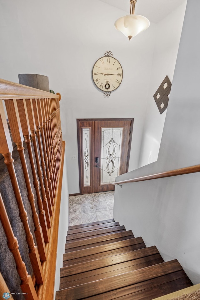 stairway featuring baseboards and a towering ceiling
