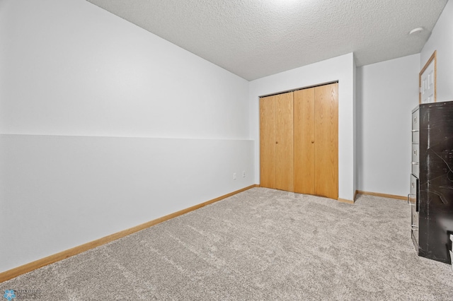 unfurnished bedroom featuring carpet floors, baseboards, a closet, and a textured ceiling