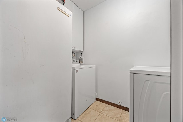 laundry area featuring cabinet space, light tile patterned floors, baseboards, and washer and clothes dryer