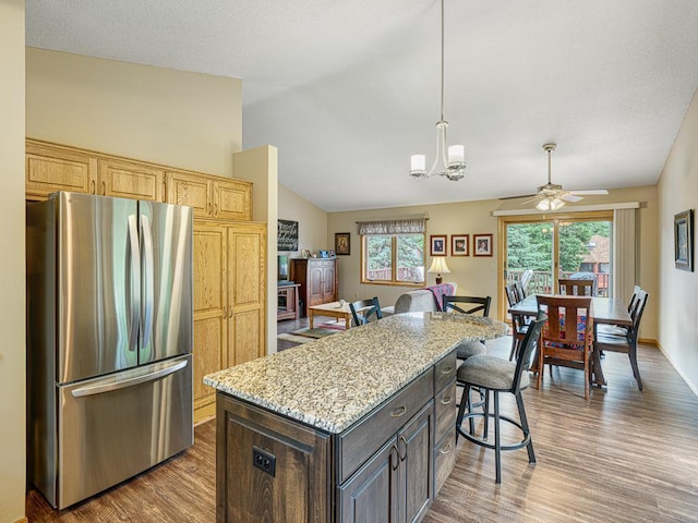 8918 Prestwick Pkwy N, Brooklyn Park, MN 55443 - kitchen featuring freestanding refrigerator, wood finished floors, a breakfast bar area, light stone counters, and a chandelier