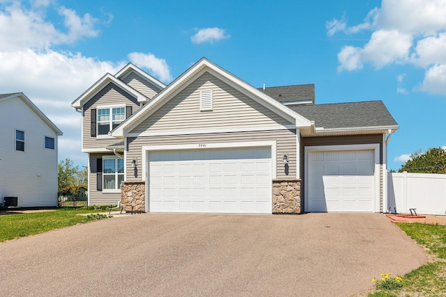 8441 152nd Ln NW, Ramsey, MN 55303 - view of front of property with stone siding, asphalt driveway, a garage, fence, and central AC unit