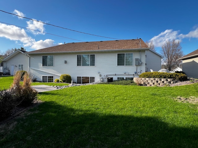 rear view of property featuring a lawn and cooling unit