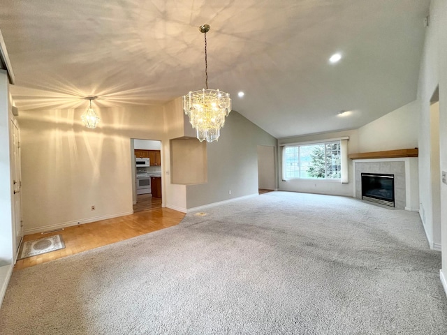 unfurnished living room featuring a notable chandelier, carpet floors, baseboards, a tile fireplace, and vaulted ceiling