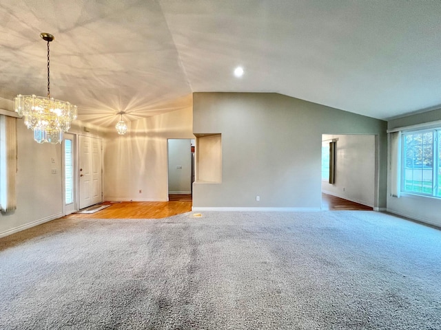 unfurnished living room with baseboards, carpet, vaulted ceiling, and a chandelier