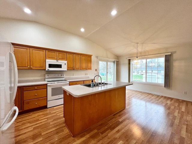kitchen featuring white appliances, a sink, lofted ceiling, and wood finished floors
