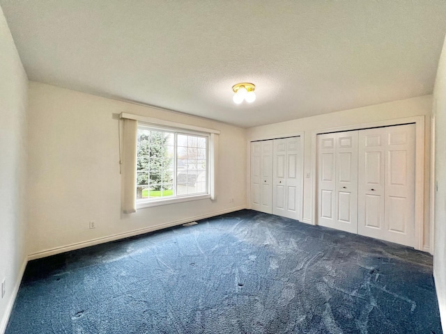 unfurnished bedroom with baseboards, carpet flooring, multiple closets, and visible vents