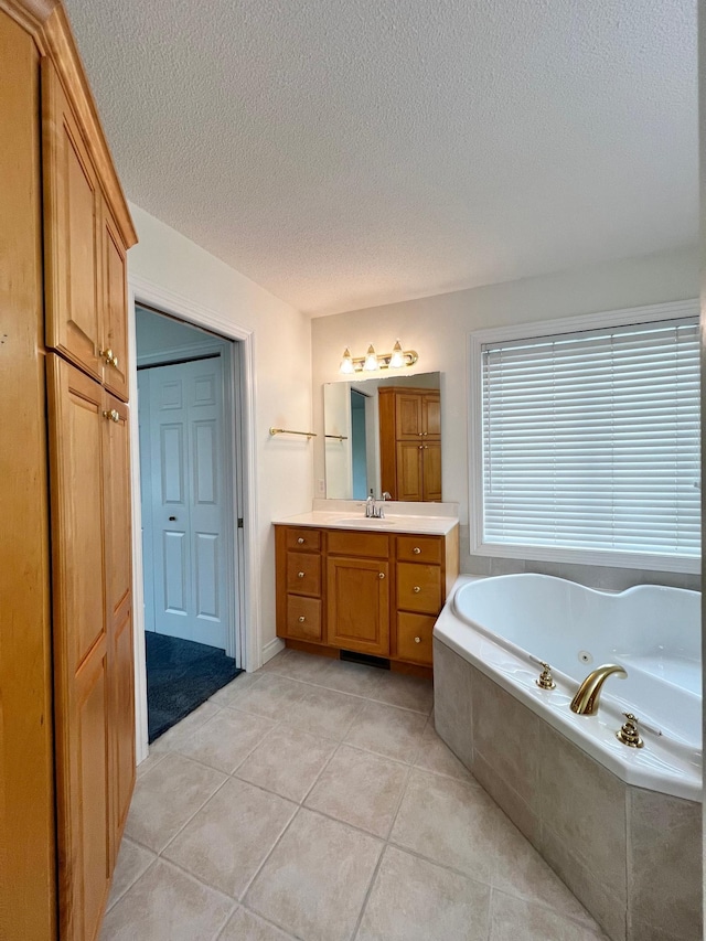 bathroom featuring a tub with jets, a textured ceiling, tile patterned flooring, and vanity