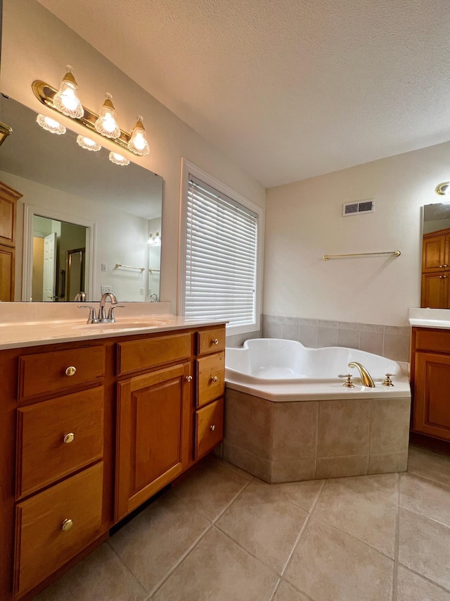 bathroom featuring tile patterned floors, visible vents, a bath, and vanity