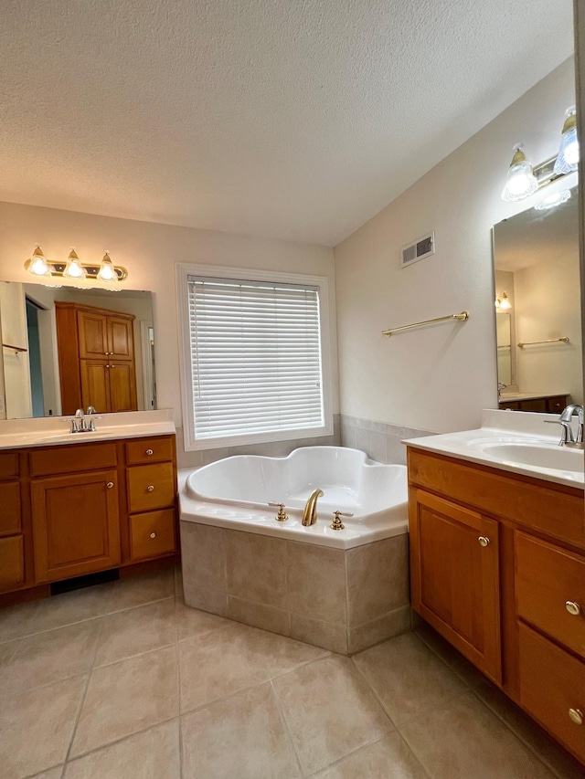 full bath with visible vents, a garden tub, a textured ceiling, tile patterned floors, and a sink