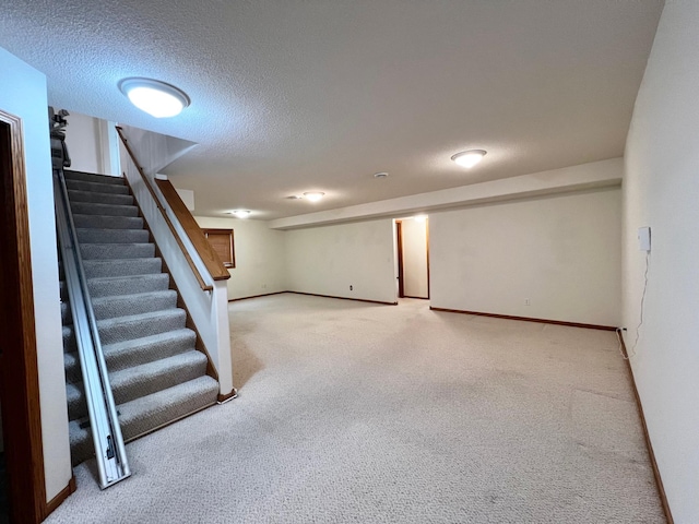 finished below grade area with baseboards, carpet, stairs, and a textured ceiling