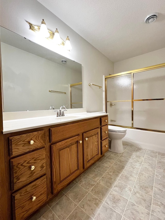 full bathroom featuring a textured ceiling, visible vents, vanity, combined bath / shower with glass door, and toilet