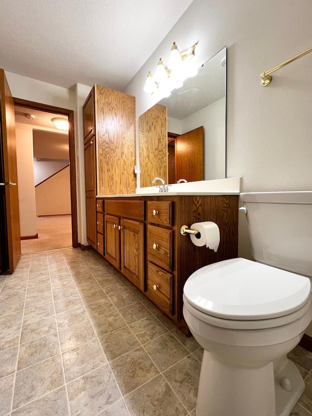 bathroom featuring vanity, toilet, and a textured ceiling
