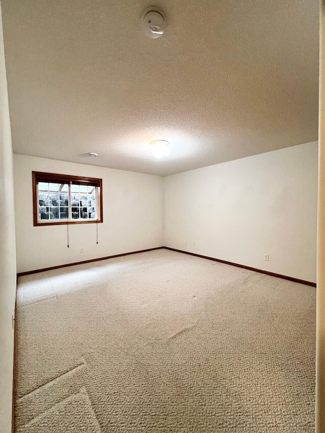 unfurnished room with baseboards, carpet flooring, and a textured ceiling