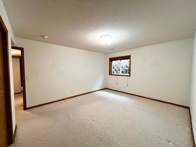 unfurnished room with baseboards, a textured ceiling, and light colored carpet