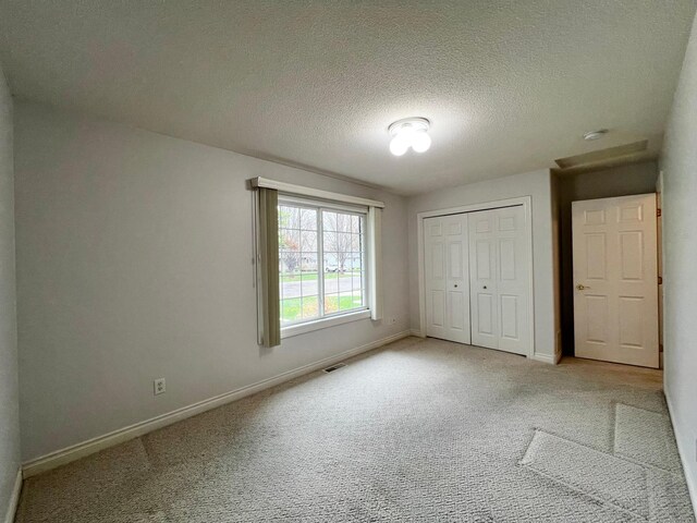1647 8th Ave, Granite Falls, MN 56241 - unfurnished bedroom with light colored carpet, a textured ceiling, visible vents, and baseboards