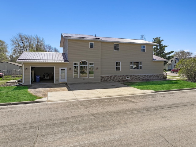 back of house with a lawn, metal roof, and a garage