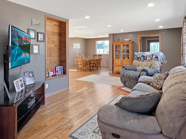 living room with recessed lighting, baseboards, and light wood-type flooring