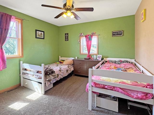 bedroom featuring carpet floors, ceiling fan, visible vents, and a textured wall