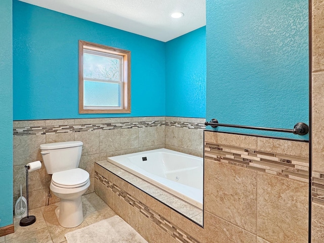 full bathroom featuring toilet, tile patterned floors, a wainscoted wall, a whirlpool tub, and tile walls