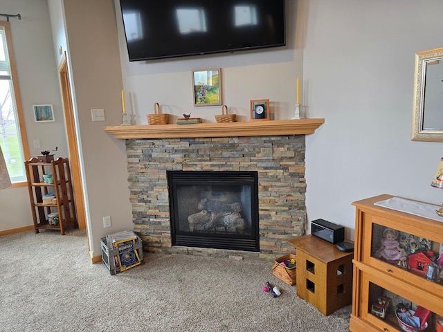 living area featuring carpet floors and a stone fireplace