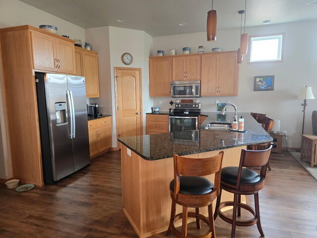 kitchen with appliances with stainless steel finishes, dark wood-style flooring, a kitchen breakfast bar, and a sink
