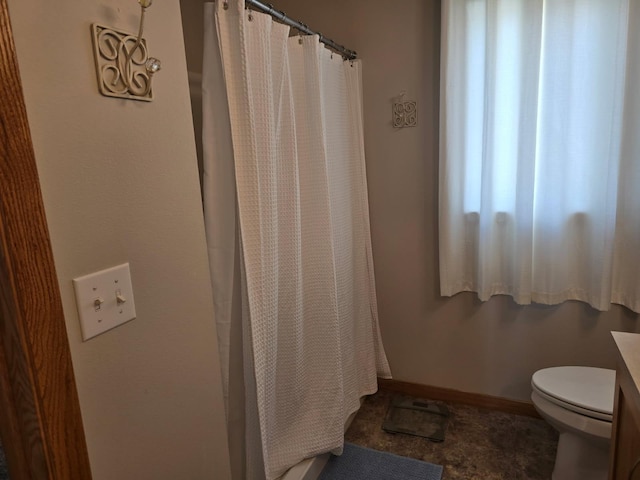 bathroom with toilet, baseboards, and a shower with curtain