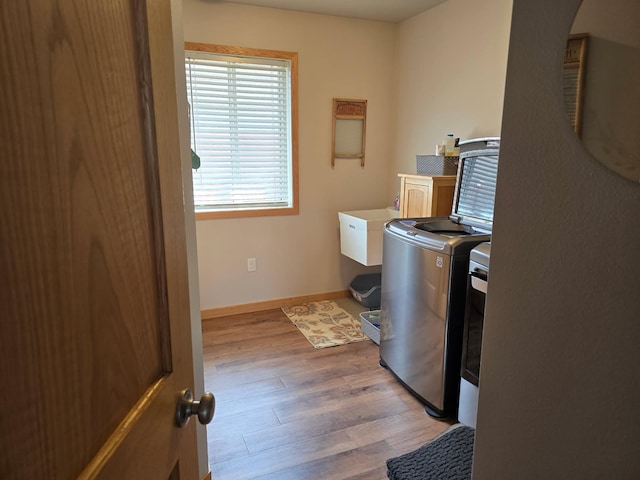 laundry area featuring light wood finished floors, cabinet space, baseboards, and washer and dryer