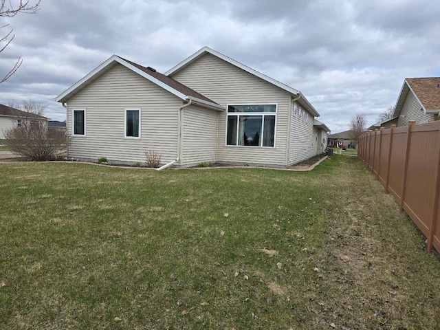 rear view of house with fence and a lawn