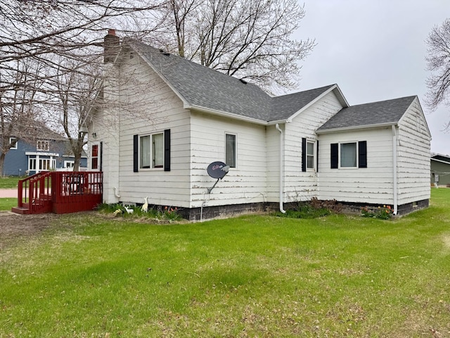 exterior space featuring a lawn, a deck, and a shingled roof