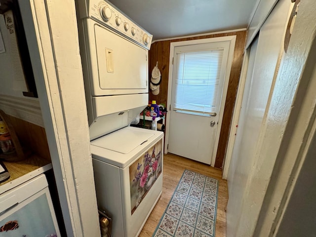 laundry area featuring stacked washing maching and dryer, light wood-style floors, and laundry area